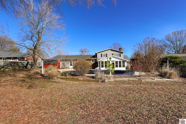 rear view of house with a chimney and fence