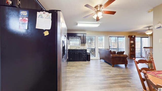 kitchen featuring stainless steel refrigerator with ice dispenser, light countertops, a ceiling fan, open floor plan, and light wood-type flooring