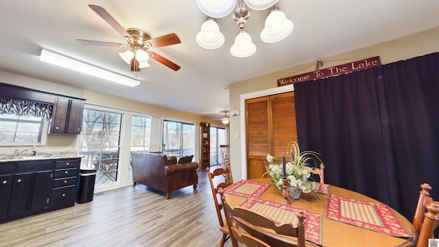 dining space featuring light wood-type flooring and ceiling fan with notable chandelier