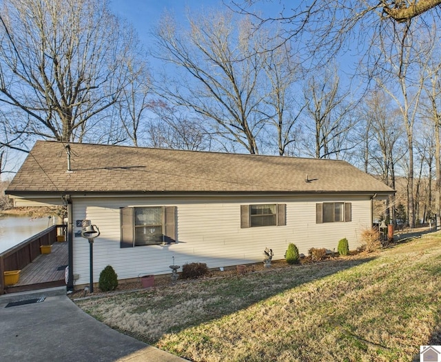 view of front facade featuring a front yard, roof with shingles, and a deck with water view