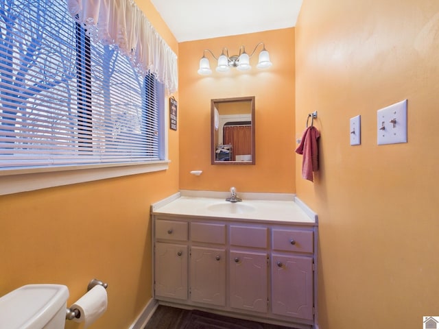 bathroom featuring baseboards, vanity, and toilet