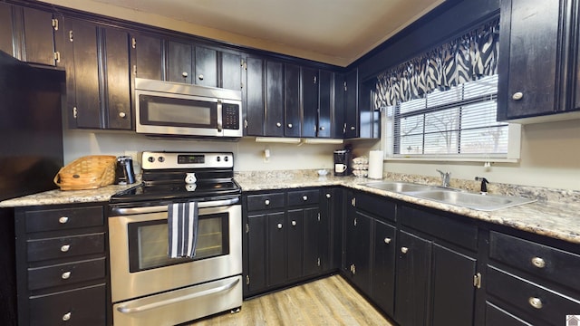 kitchen with stainless steel appliances, light wood-style floors, light countertops, and a sink