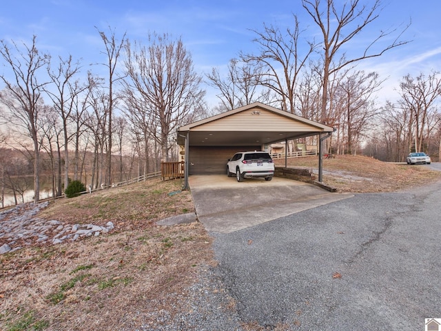 view of property exterior with driveway, a carport, and fence