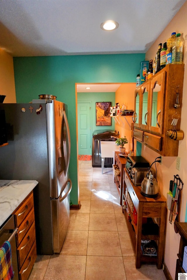 kitchen featuring light stone counters, light tile patterned flooring, recessed lighting, baseboards, and stainless steel fridge