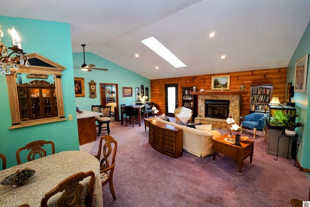 living area with vaulted ceiling with skylight, recessed lighting, wood walls, a fireplace, and carpet flooring