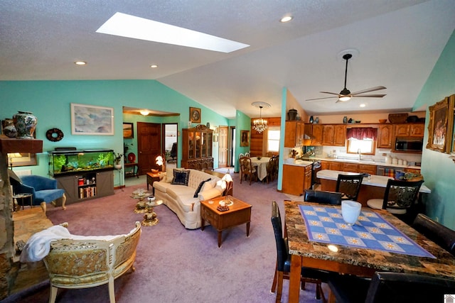 living area with ceiling fan with notable chandelier, vaulted ceiling with skylight, recessed lighting, and light colored carpet