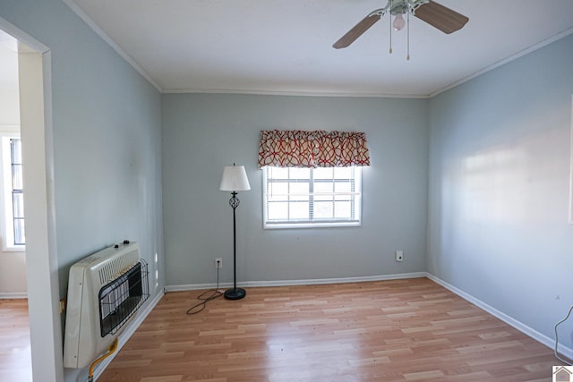 unfurnished living room with heating unit, light wood-type flooring, baseboards, and crown molding