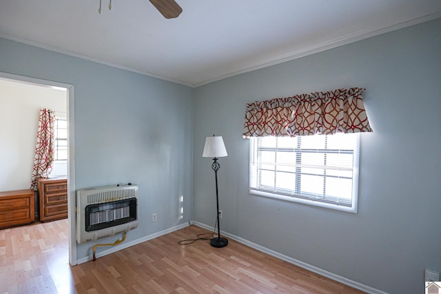 interior space with baseboards, ceiling fan, ornamental molding, wood finished floors, and heating unit