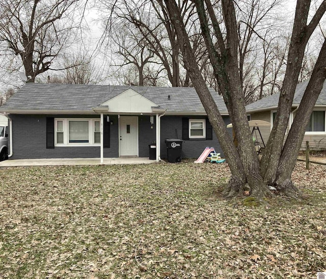 ranch-style house featuring roof with shingles and brick siding