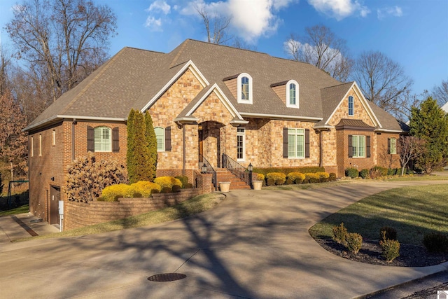 view of front of property with a shingled roof, concrete driveway, and brick siding