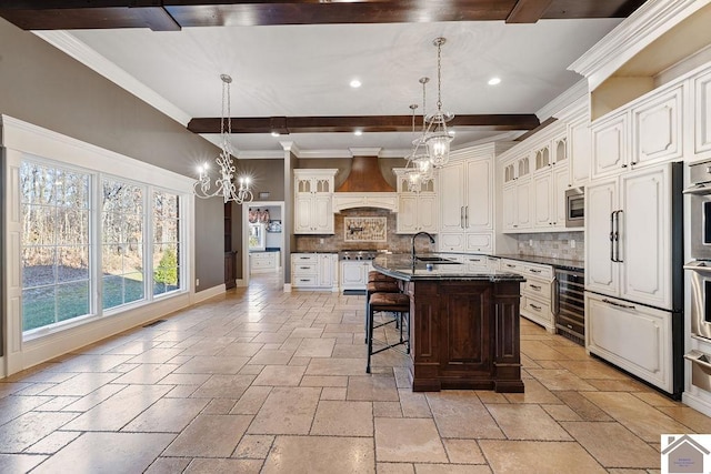 kitchen featuring stone tile floors, wine cooler, appliances with stainless steel finishes, an inviting chandelier, and premium range hood