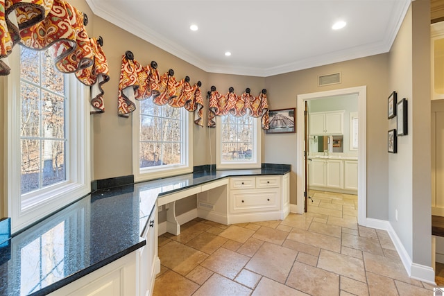 interior space with stone tile floors, baseboards, visible vents, built in study area, and ornamental molding