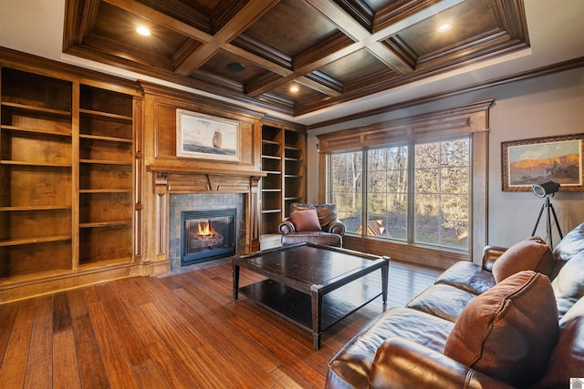 living area featuring beam ceiling, coffered ceiling, crown molding, and a tile fireplace