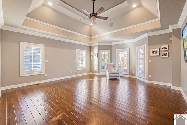 interior space featuring ornamental molding, a tray ceiling, hardwood / wood-style flooring, and baseboards