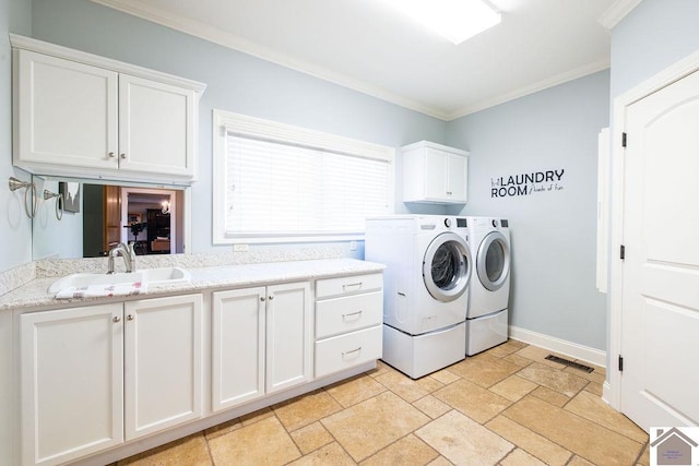 washroom featuring washing machine and dryer, a sink, visible vents, cabinet space, and crown molding