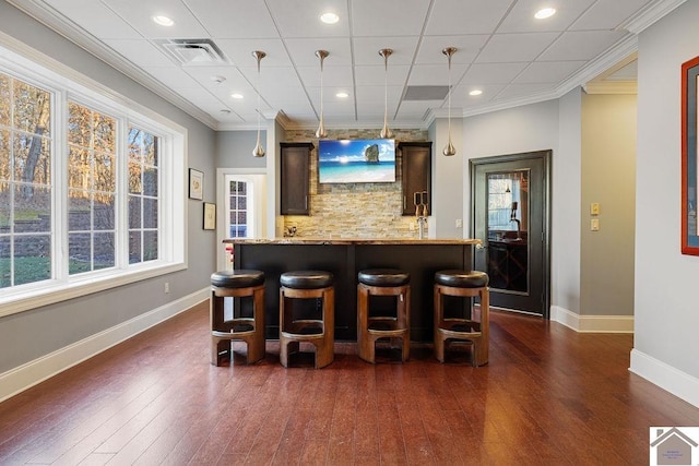 bar featuring dark wood-type flooring, visible vents, baseboards, ornamental molding, and decorative backsplash