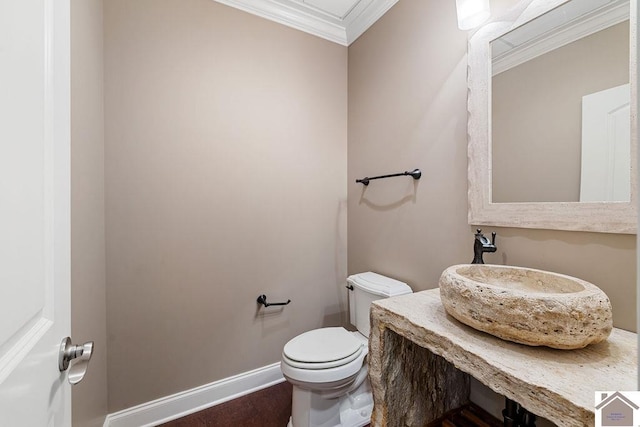 half bathroom featuring ornamental molding, baseboards, a sink, and toilet