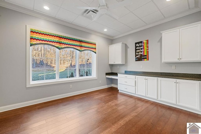 kitchen with ceiling fan, baseboards, white cabinets, built in study area, and dark countertops