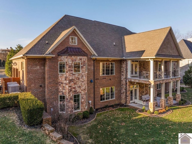 back of property featuring french doors, a yard, a patio, a balcony, and stone siding