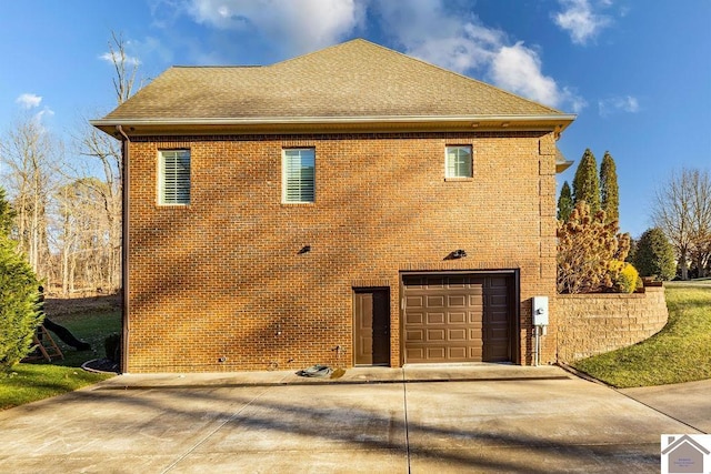 view of side of property featuring concrete driveway, brick siding, roof with shingles, and an attached garage