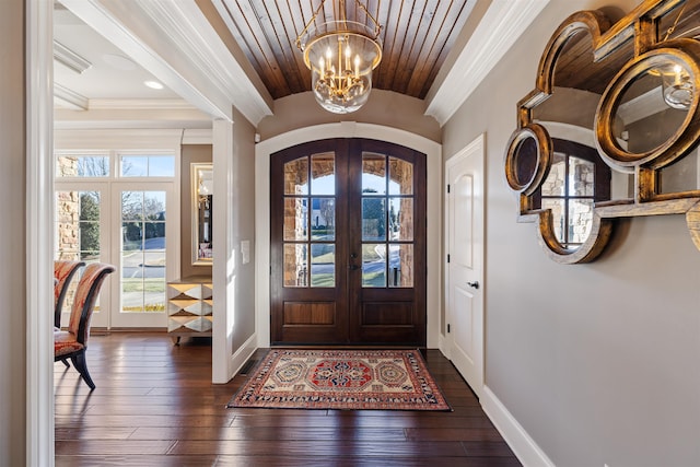 foyer with ornamental molding, dark wood-style flooring, a notable chandelier, and french doors