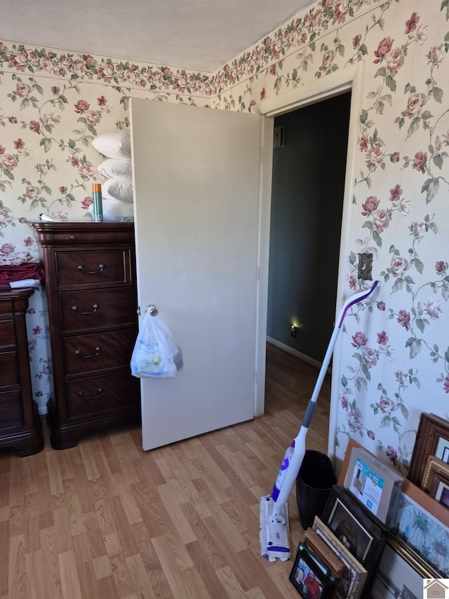 bedroom with wallpapered walls, baseboards, and light wood-style floors