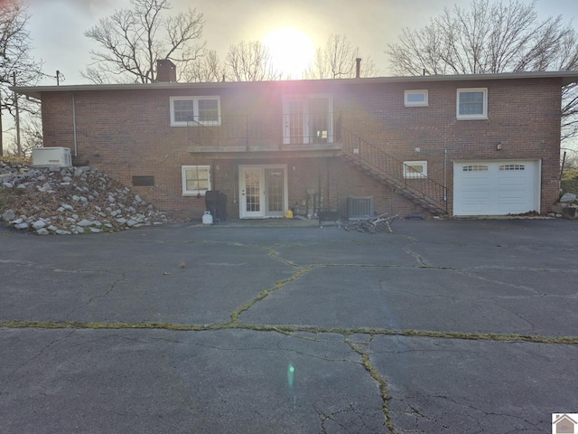 rear view of property with central AC, brick siding, stairs, french doors, and a chimney