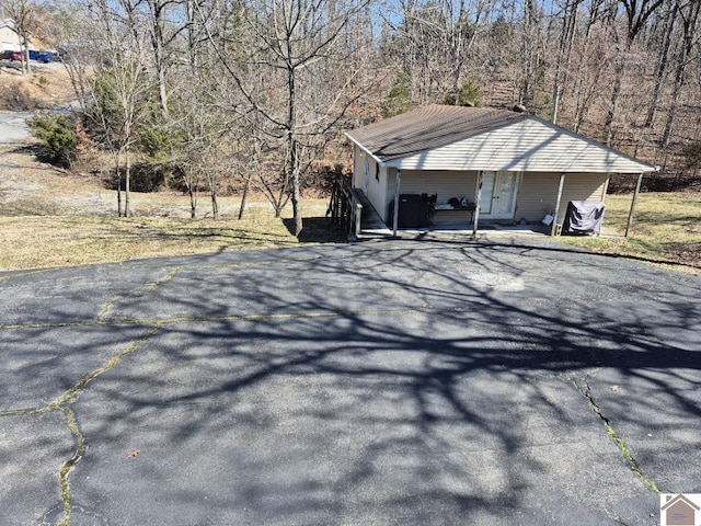 view of side of property featuring covered porch and aphalt driveway