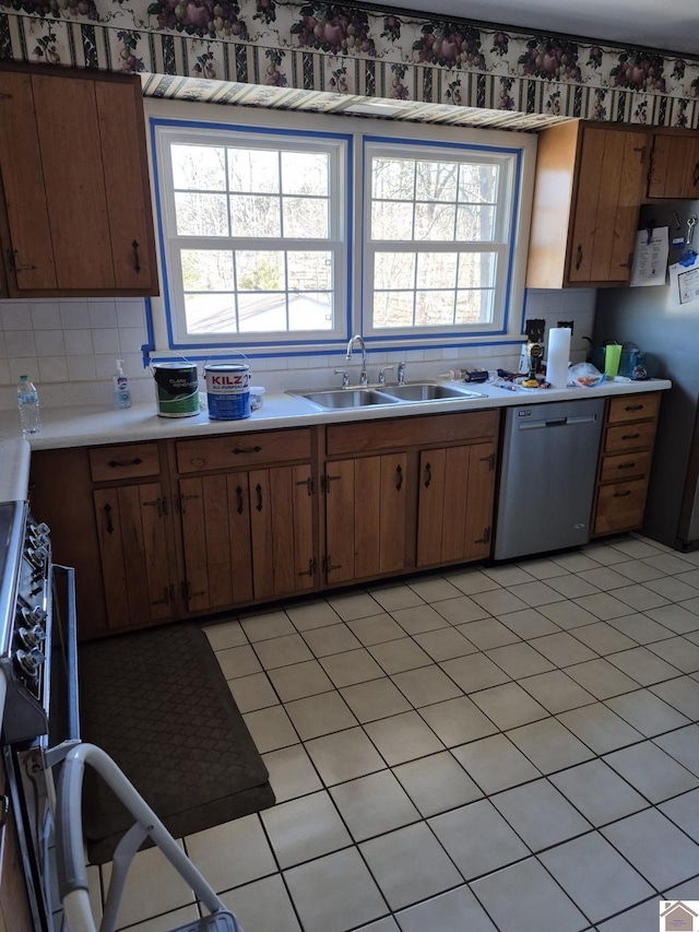 kitchen with tasteful backsplash, dishwasher, brown cabinets, light countertops, and a sink