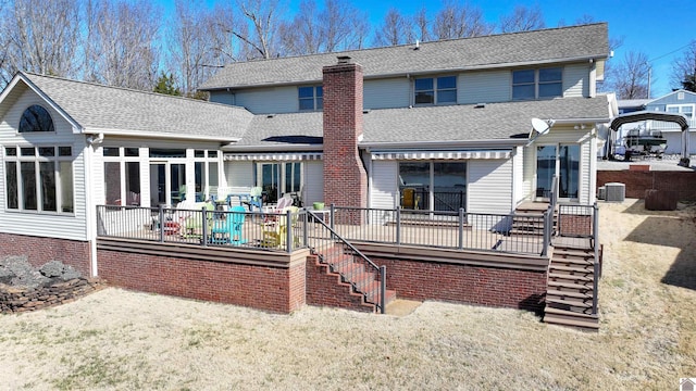 back of house featuring a chimney, roof with shingles, a lawn, and stairway