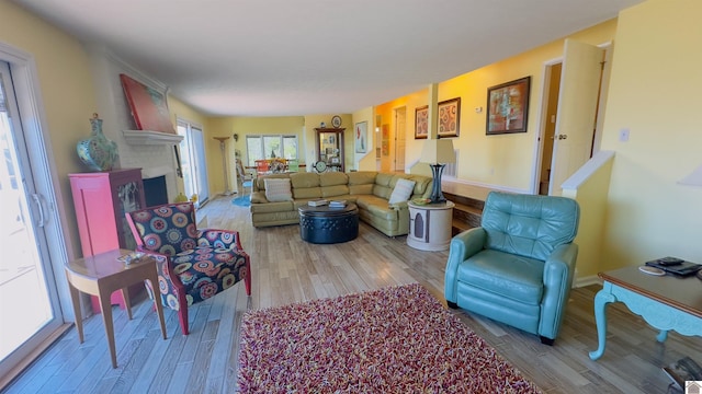 living area with a fireplace, baseboards, and wood finished floors