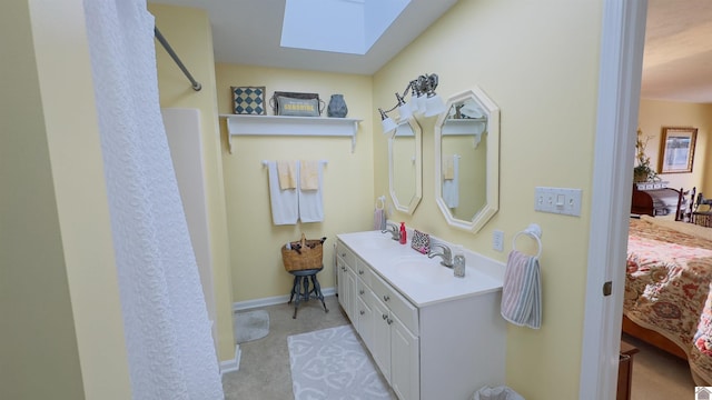 ensuite bathroom featuring double vanity, a skylight, ensuite bath, and a sink