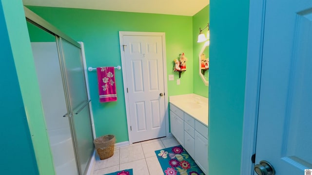 full bathroom with a stall shower, tile patterned flooring, vanity, and baseboards