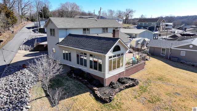 rear view of property with a lawn, a chimney, and a residential view