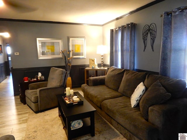 living room featuring light wood-type flooring, crown molding, and wainscoting