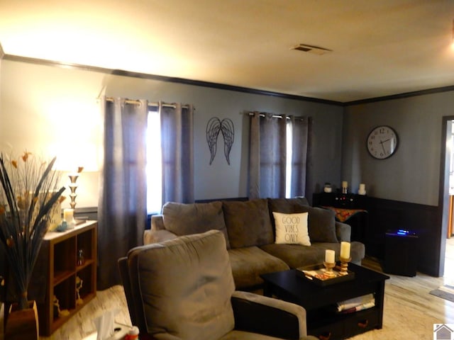 living room featuring light wood finished floors, visible vents, and crown molding