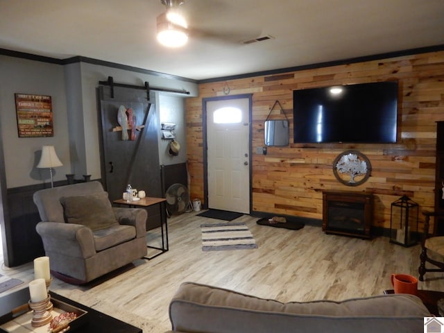 living area featuring ornamental molding, a barn door, and wood finished floors