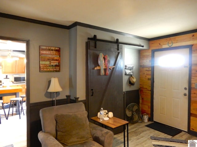 entrance foyer featuring a barn door, crown molding, and wood finished floors