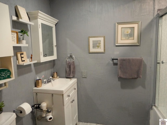 bathroom with toilet, a shower with door, and vanity