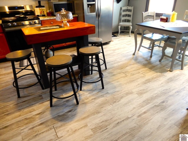 dining area with light wood finished floors and bar area