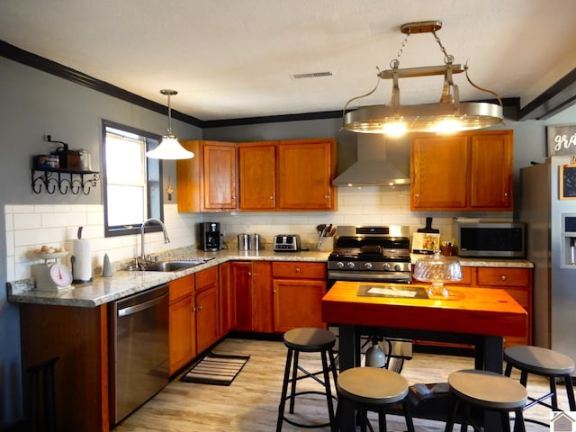 kitchen featuring visible vents, backsplash, appliances with stainless steel finishes, a sink, and wall chimney exhaust hood