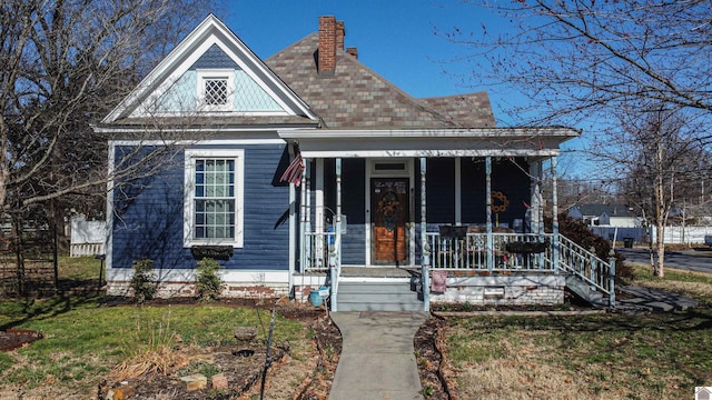 victorian home with a porch, a chimney, and a front yard