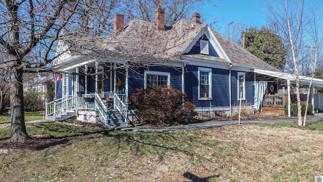 view of front facade with roof with shingles, a porch, and a front lawn