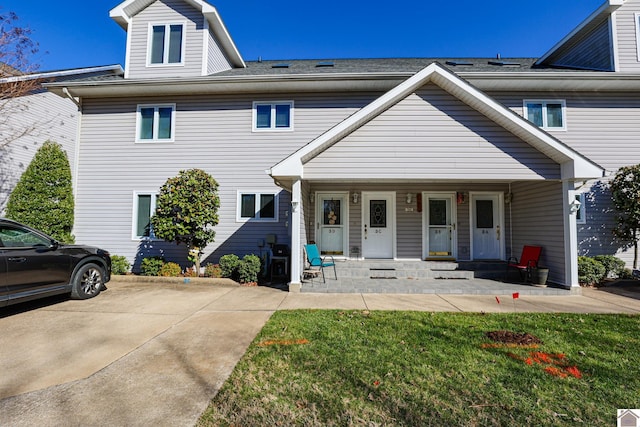 view of property featuring covered porch and a front yard