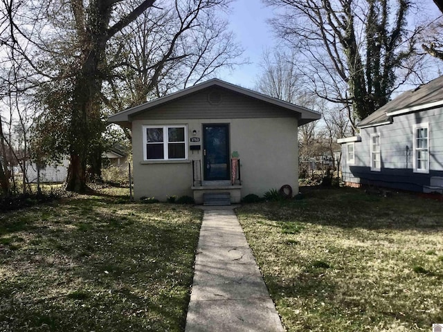 bungalow-style home with a front yard and stucco siding