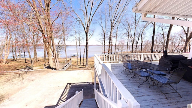 deck with outdoor dining area and a water view