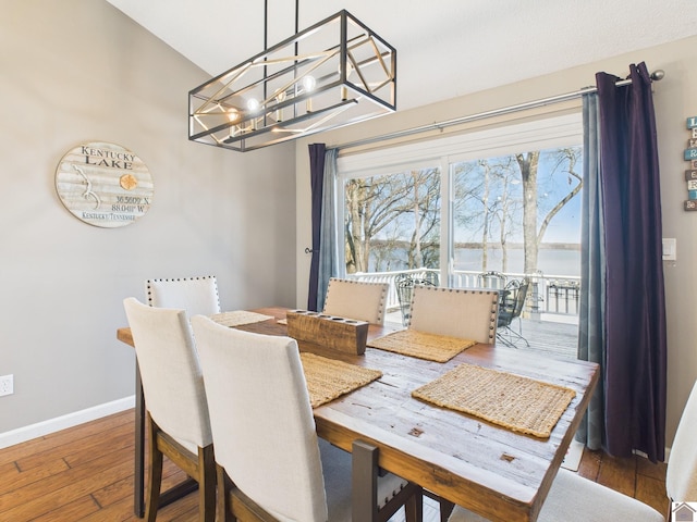 dining space featuring baseboards, hardwood / wood-style floors, and a notable chandelier