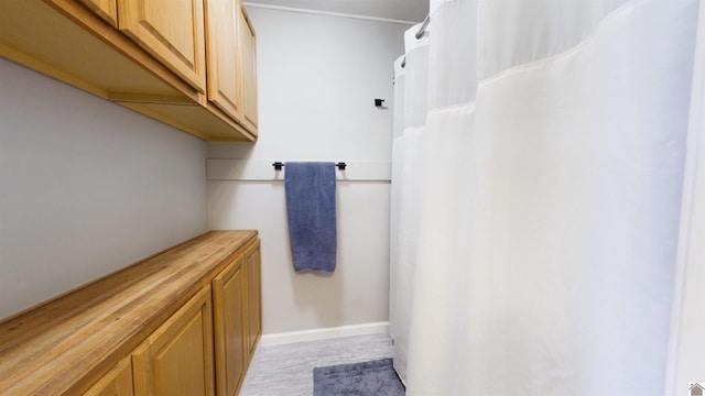 full bath featuring curtained shower and baseboards