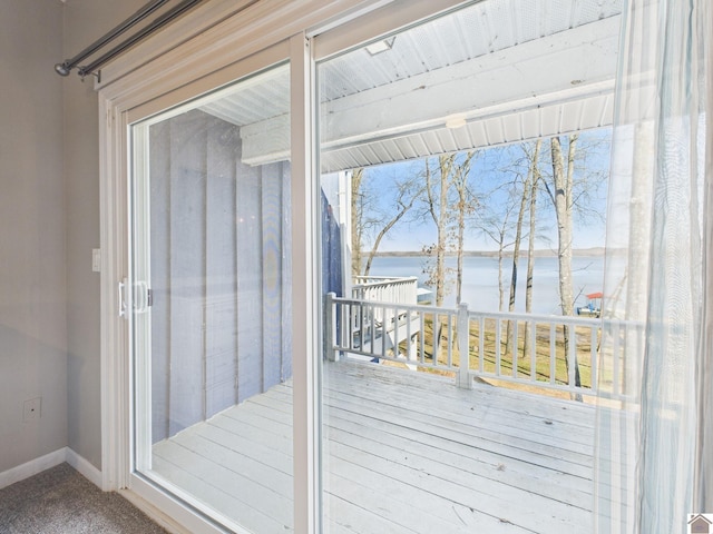 entryway featuring a water view, baseboards, and carpet floors