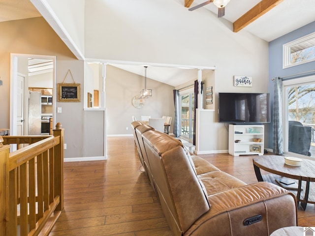 living room featuring high vaulted ceiling, beamed ceiling, baseboards, and hardwood / wood-style flooring